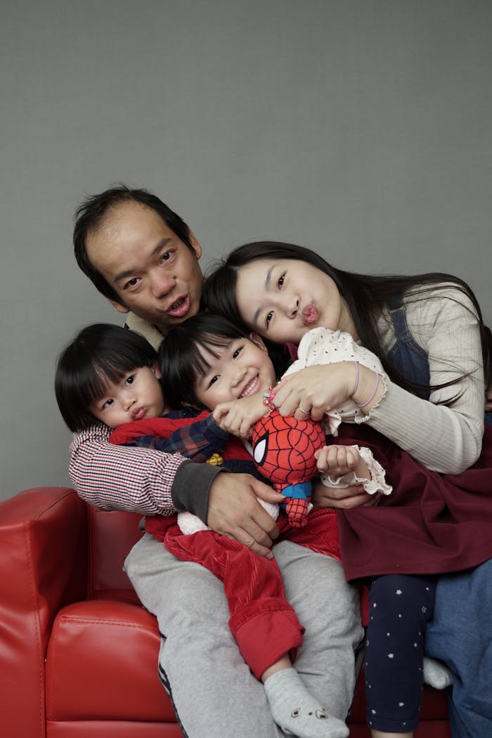 Crafting Captivating Headlines: Your awesome post title goes here A joyful family of four posing together on a red couch in a Hong Kong studio.