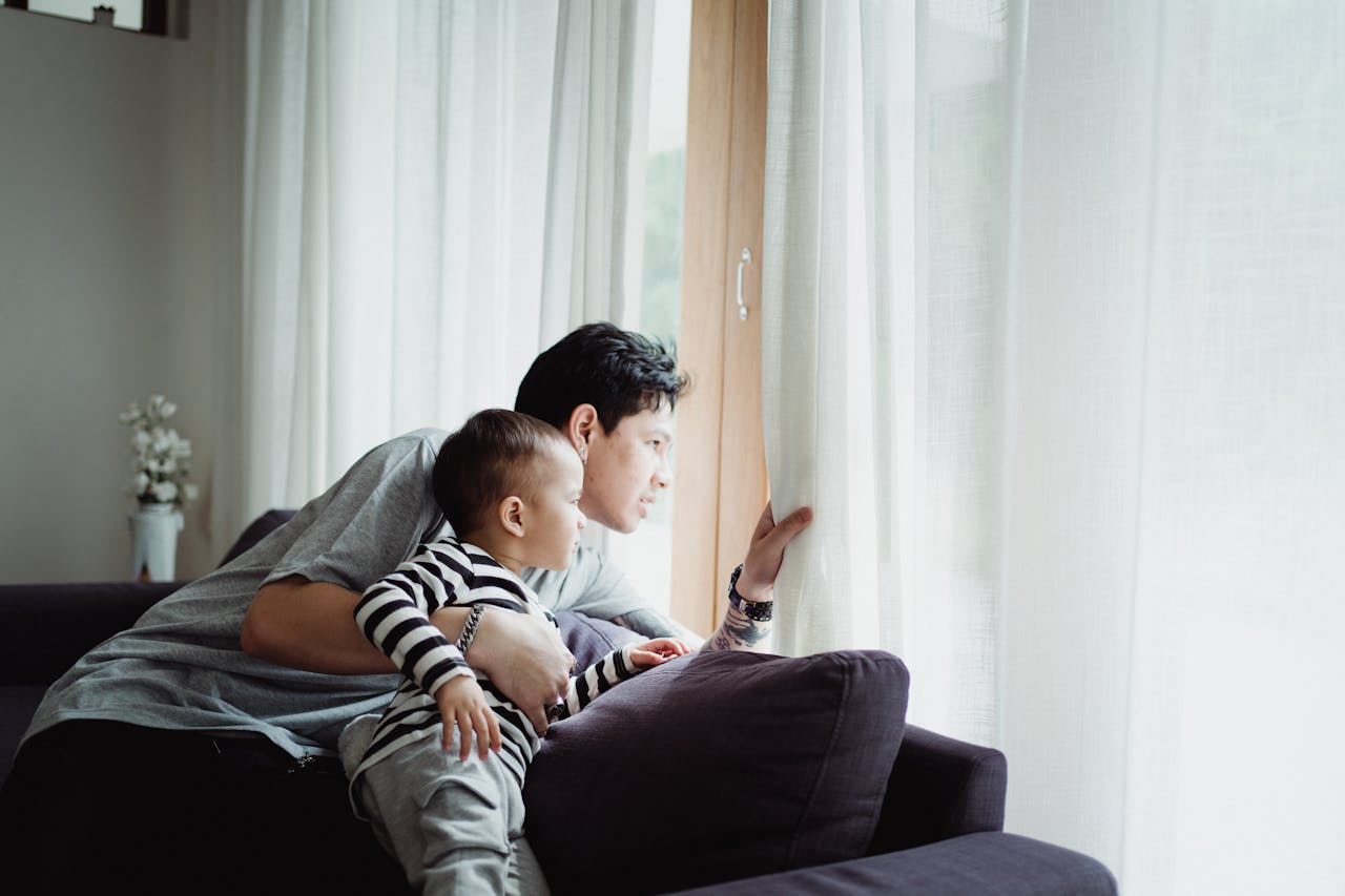 about-us Father and son looking out the window together, capturing a serene family moment indoors.